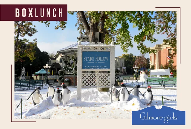 BoxLunch and Gilmore Girls graphic showing the Stars Hollow town sign with snow and penguin decorations on the Warner Bros. set.