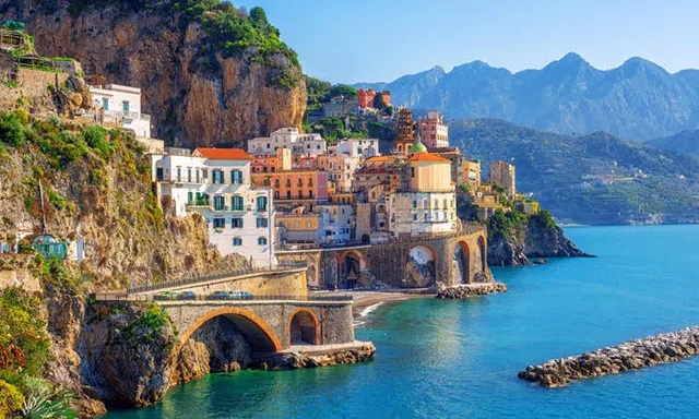 Photo of a colourful Italian coastal town on a bay with mountains behind, used on the Times Radio and Times Holidays prize page.