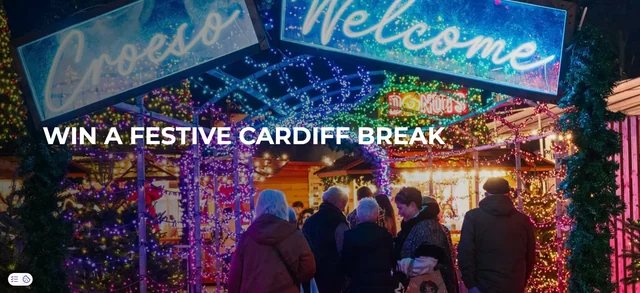 Official Visit Cardiff festive-break promotion page showing a Christmas market scene and the headline win a festive Cardiff break.